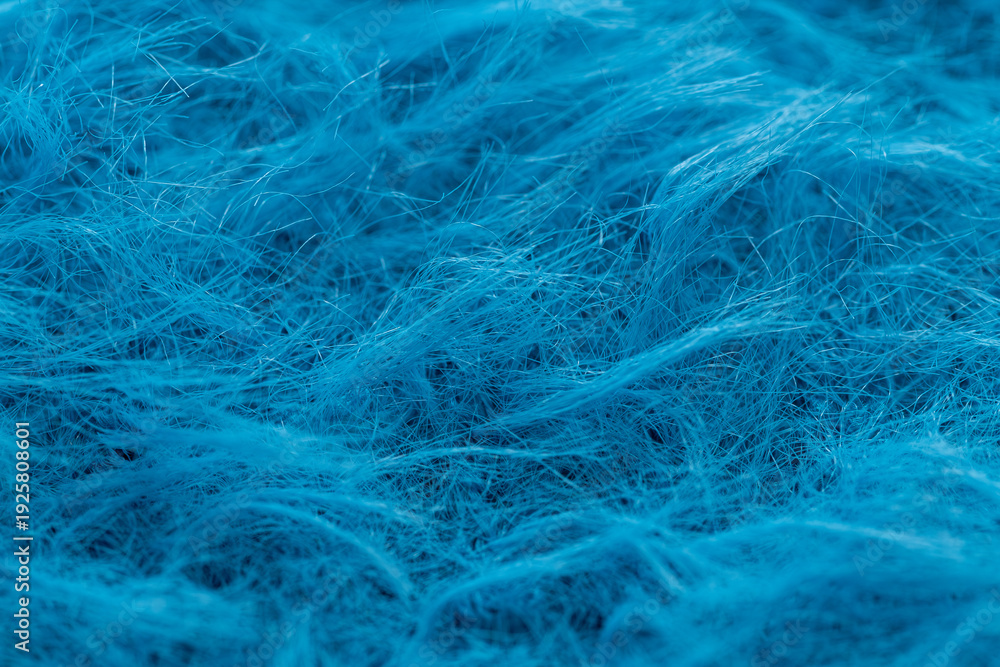 Fototapeta premium Macro shot of soft blue mohair wool texture. Close-up of fuzzy and fluffy blue yarn fibers for knitting and textile background.
