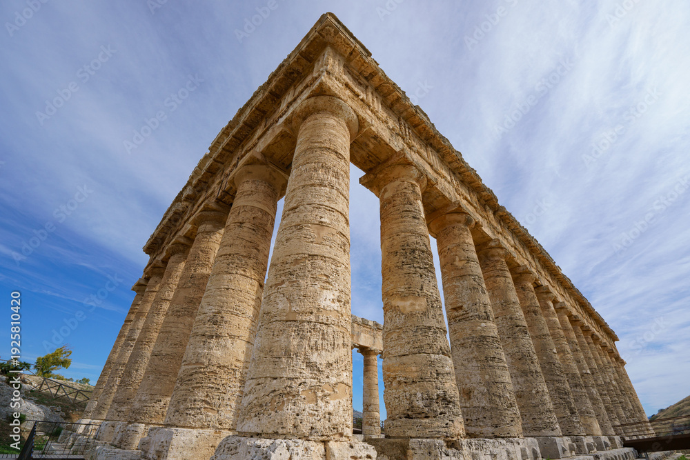 Fototapeta premium Wide Low-Angle View of the Doric Temple of Segesta Against a Dramatic Blue Sky with White Clouds, Sicily