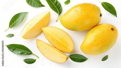 Two whole mangoes and several slices are cut and placed next to green leaves on a clean white surface. The setting is bright and shows the mango's fresh color