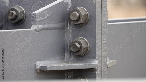 The connection between two steel beams (trusses) with threaded metal bolts. The steel beam is gray.
