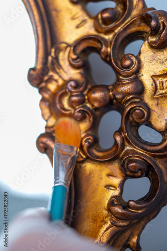 Photos Art conservator restoring golden mirror frame, antique detail closeup, delicate