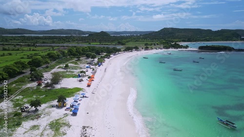 Wallpaper Mural Aerial Turquoise Beach With Lined Umbrellas, Families Strolling Along Shallow Waters, Boats Moored Near Sandbar, Grassy Dunes And Picnic Setups, Bright Summer Mood And Coastal Relaxation,Tanjung Aan Torontodigital.ca