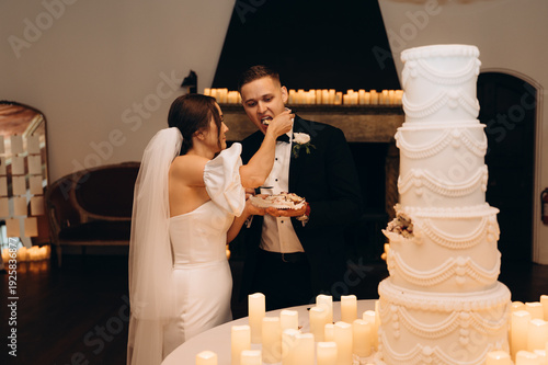 Couple sharing cake during elegant celebration indoors, romantic moment with dessert, candles and festive atmosphere.