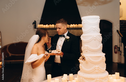 Couple sharing cake during elegant celebration indoors, romantic moment with dessert, candles and festive atmosphere.