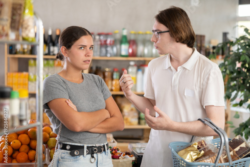 Bild auf Leinwand Husband and wife are standing in front of each other, shouting and swearing, quarreling while shopping at grocery store