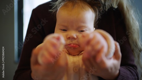 Wallpaper Mural Close up of a baby sitting on an adult's lap indoors while gently holding hands Torontodigital.ca