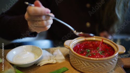 Wallpaper Mural Close up of a hand holding a spoon above a bowl of borscht garnished with herbs Torontodigital.ca