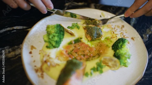 Wallpaper Mural Close up of hands using knife and fork to cut a salmon fillet served with broccoli and sauce Torontodigital.ca