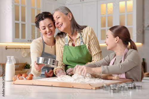 Принти на полотні Smiling grandmother, her daughter and granddaughter cooking together at white ma
