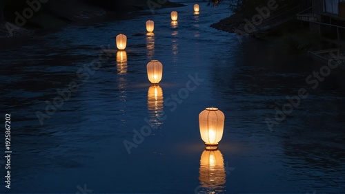 Several small, illuminated paper lanterns drift slowly downstream on a dark river, their warm light reflecting off the smooth, cool surface under a night