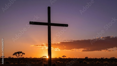 Dramatic silhouette of a weathered wooden cross against a fiery, deep orange and purple Australian Good Friday sunset over scrubland landscape.