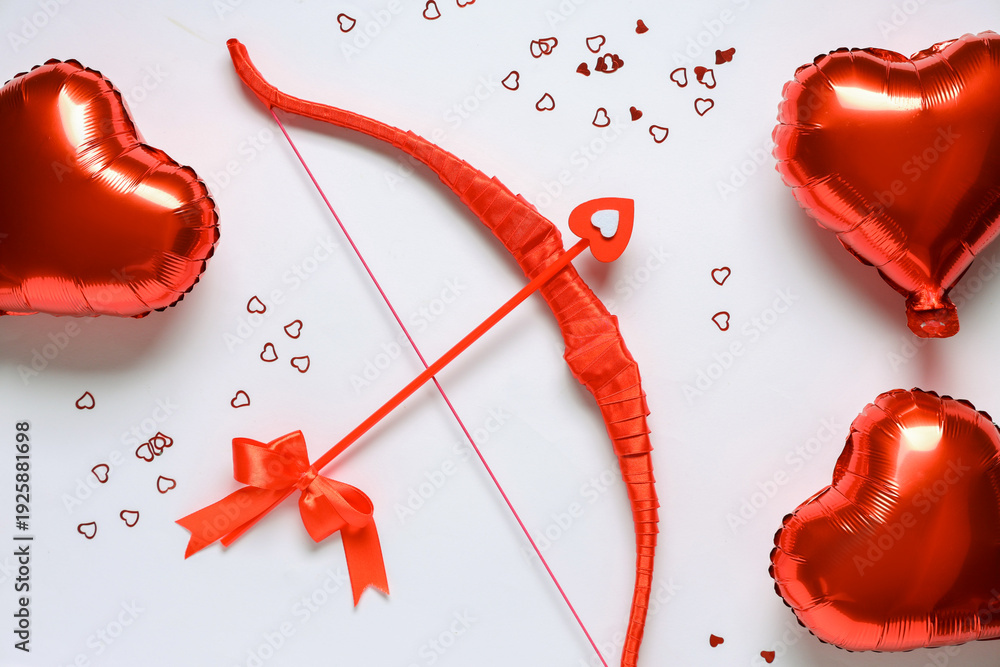 Naklejka premium Composition with red cupid's bow and heart shaped balloons on light background. Valentine's Day celebration