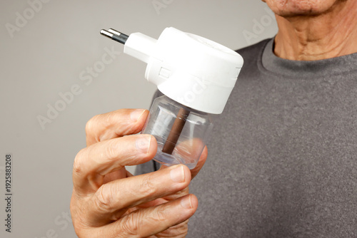Man Holding up and demonstrating An Electric Plug in Mosquito Repellent for home use