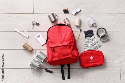 Φωτογραφία Emergency backpack and necessities on floor at home, top view