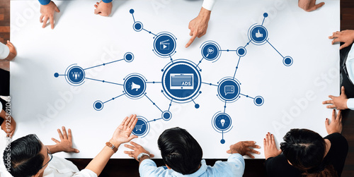 Photos A diverse group of professionals collaborates around a table, visualizing digital advertising strategies through graphical representations of data and advertising concepts