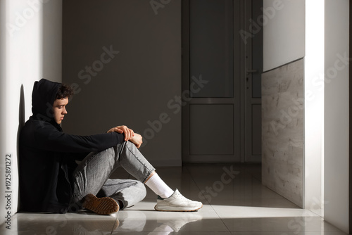 Sad young man sitting on fl...