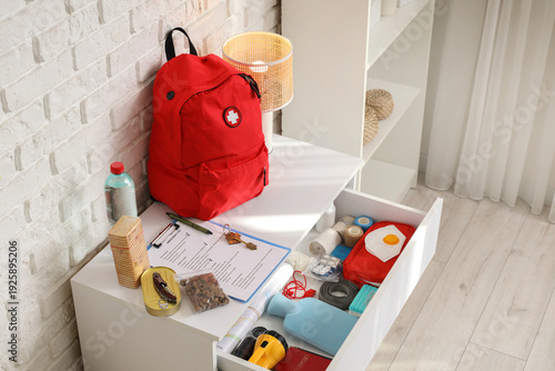 Photos Chest of drawers with necessities and emergency backpack in room