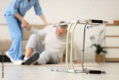 Cuadro en lienzo Walker against nurse helping senior man to stand up after fall at home, closeup