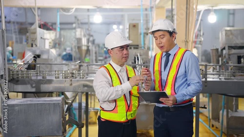 Asian man factory engineers and manager quality control inspection in canned food manufacturing plant review production line with safety equipment and industrial processing inside modern food factory.