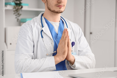 Male doctor meditating at desk in clinic, closeup
