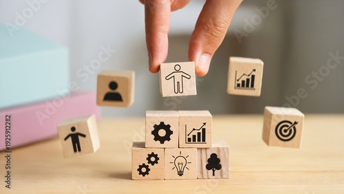 Change management concept featuring a hand stacking wooden blocks with icons of strategy, growth, learning, leadership, and teamwork, representing organizational transformation and business developmen
