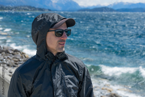 Male traveler portrait, outdoor adventure, dark jacket, sea background