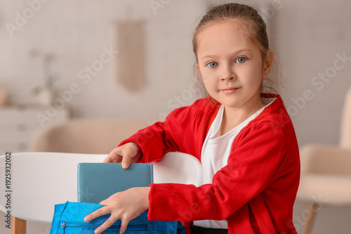 Cute little girl putting bo...