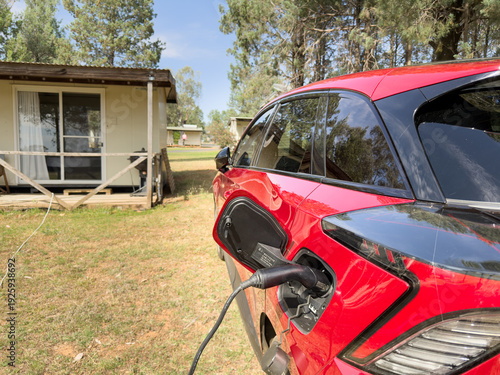 Electric car EV plugged in and charging with a type 2 granny cable at a rural holiday cabin campsite
