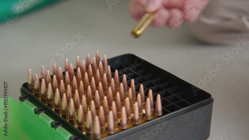 Close up, An ammunition box with a bullet being lifted out and checked and placed back inside the box.