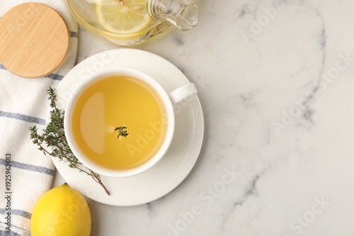 Quadro em tela Fresh thyme tea in cup and lemon on white marble table, flat lay