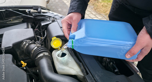 Cuadro en lienzo A man is pouring windshield washer fluid into the car's reservoir