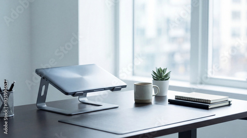 Fotografi Minimalist home office setup with laptop stand, coffee mug, and plant on a wooden desk, bright natural light from window