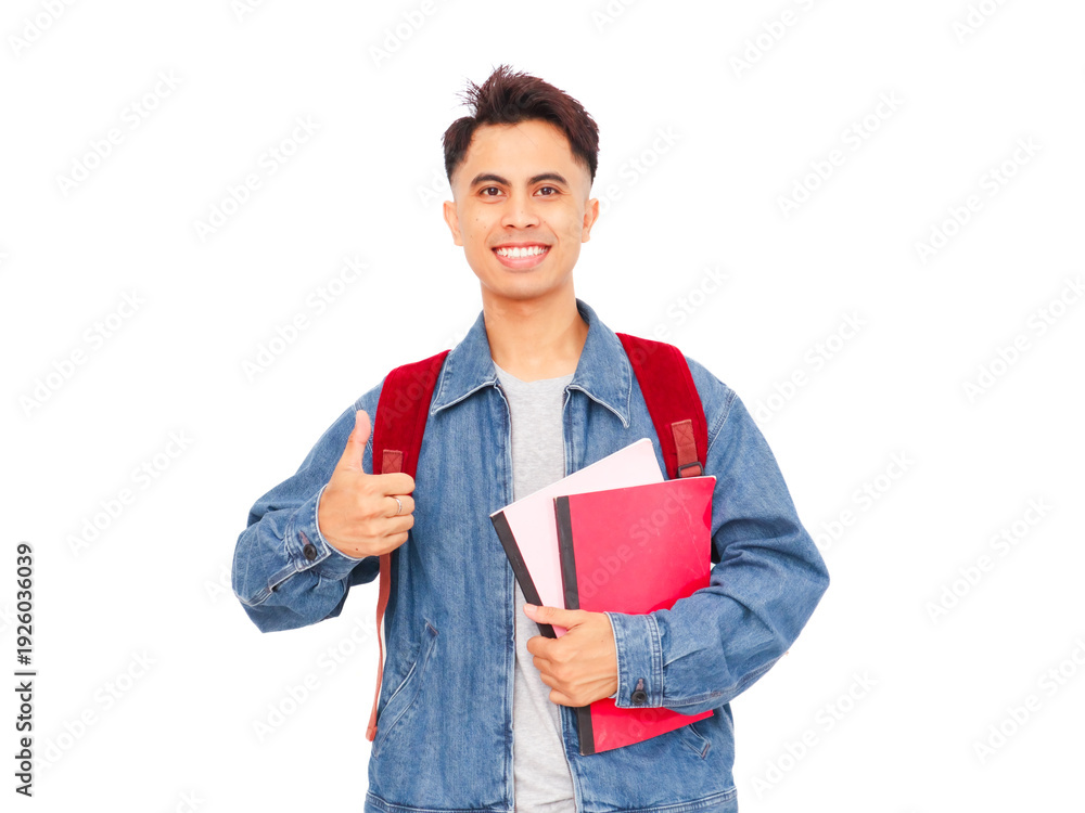 Obraz premium Smiling Asian male college student holding book and backpack giving thumb up on white background