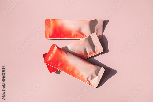 Bild auf Leinwand Three empty rectangular sachets on pink surface with harsh shadows