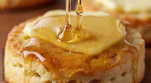 A stream of golden honey being drizzled over a buttered biscuit. Style Slow-motion, sensual food film