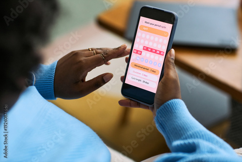 Photos Black woman using smartphone tracking menstrual cycle with femtech health app, h