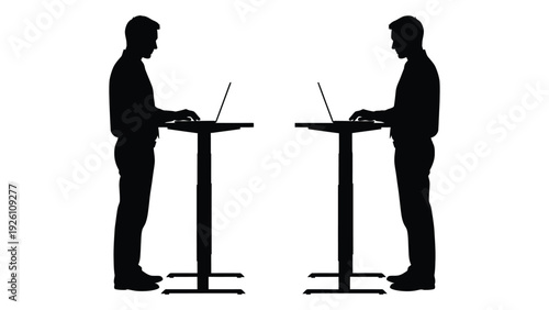 Two silhouettes of people standing and using laptops at high desks