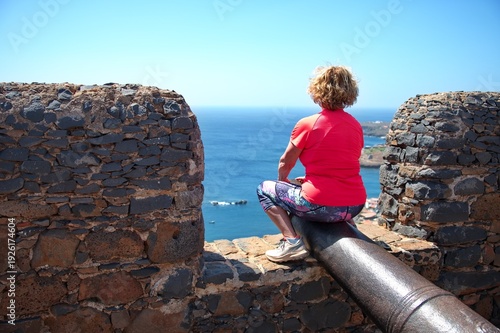 Senior woman sitting on a gun on the fortress in Cape Verde