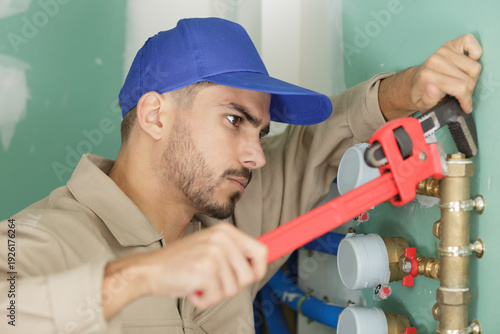 Bild auf Leinwand male plumber fixing water meter with adjustable wrench