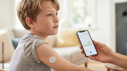 Wallpaper Mural Young child wearing wearable biosensors patch upper arm monitored by smartphone app showing glucose monitoring graph and caregiver assisting with Torontodigital.ca