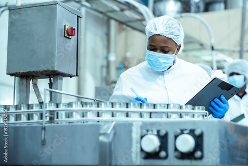 Quadro em tela Manufacturing supervisor checks batch of canned food products on assembly line while following safety protocol in processing plant, representing industrial efficiency and compliance control