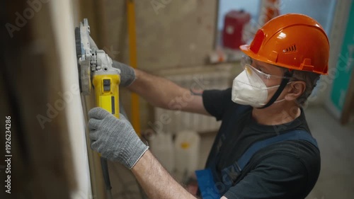 Construction worker sanding a wall with an electric sander