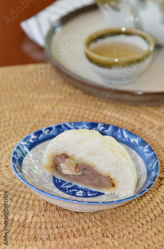Taro-filled steamed buns with hot tea cup at back