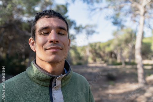 Φωτογραφία Young man meditating eyes closed in nature forest