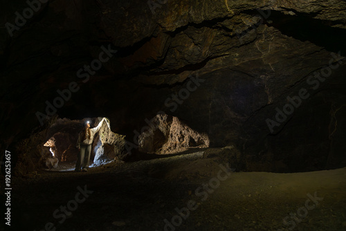 Woman exploring dark underground cave with headlamp