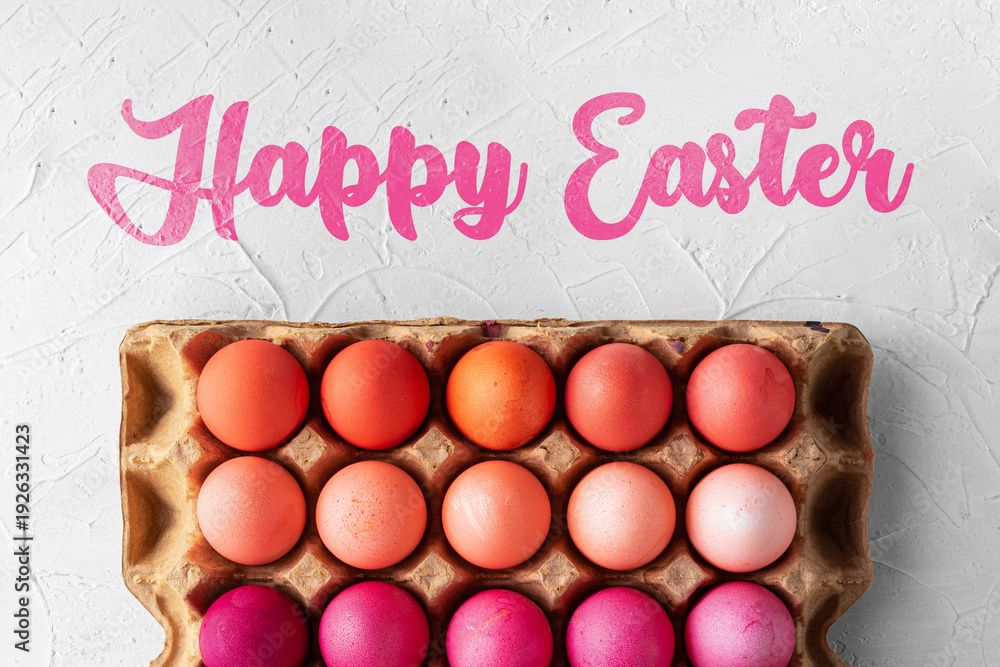 Fototapeta premium Easter celebration with colorful eggs in a carton and festive greetings above them