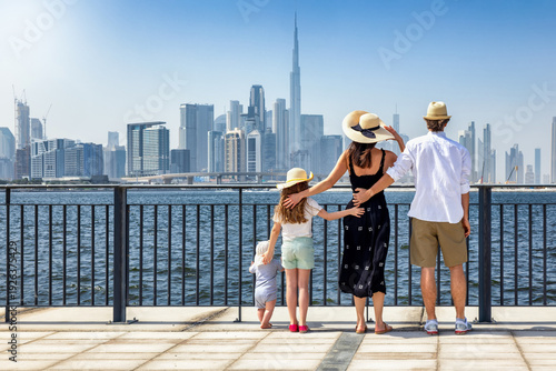 Photography A tourist family of four looks together at the urban skyline of Dubai, UAE, duri