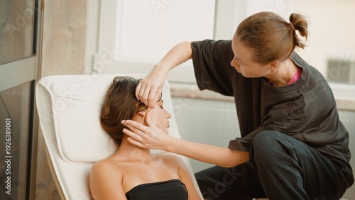 Beauty specialist administers facial and jaw therapy in bright room