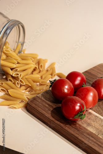  Spilled Penne Pasta and Fresh Cherry Tomatoes on Wooden Board