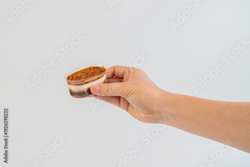 Wallpaper Mural Three-layered brownie cake topped with crunchy topping in a clear cup and hand. Torontodigital.ca